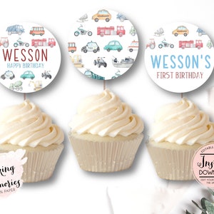 Op de afbeelding: Drie cupcakes met witte glazuur, elk bekroond met een ronde decoratie met voertuigillustraties. E&eacute;n zegt "Wesson Happy Birthday", een andere zegt "Wesson's First Birthday".