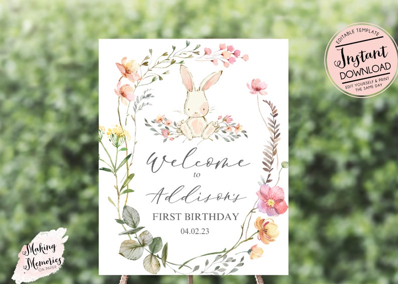 May include: A printable welcome sign for a first birthday party. The sign features a watercolor illustration of a white bunny rabbit surrounded by pink and yellow flowers. The text on the sign reads "Welcome to Addison's First Birthday 04.02.23".