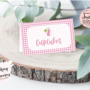 May include: Pink and white gingham food label with a golf bag icon and the text "Cupcakes".