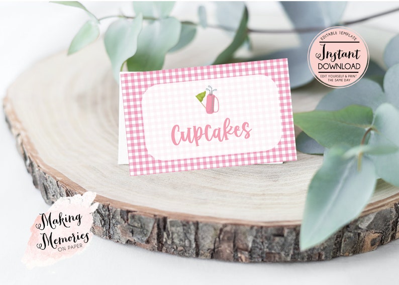 May include: Pink and white gingham food label with a golf bag icon and the text "Cupcakes".