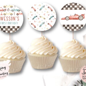 May include: Three cupcakes with toppers featuring race car designs. One topper says "Wesson's First Birthday" with race cars. Another has a pattern of race cars and flags. The third shows a red race car.