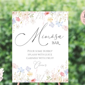 Pu&ograve; includere: Un cartello stampabile con un design floreale e il testo "Mimosa Bar". Il cartello indica agli ospiti di "Versare un po' di bollicine, aggiungere del succo, guarnire con frutta, Salute!"