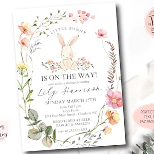 May include: A white bunny with pink ears sits in a wreath of watercolor flowers. The text "A Little Bunny Is On The Way!" is above the bunny. The text "Lily Harrison" is below the bunny. The text "Sunday March 15th" is below the name. The text "from 5 til 7 pm" is below the date. The text "Lily's Farm" is below the time. The text "1234 East Main Street - Charlotte NC" is below the farm name. The text "Registered at Belk, Target & Amazon" is below the address. The text "rsvp to 233.123.1233" is below the registry information.