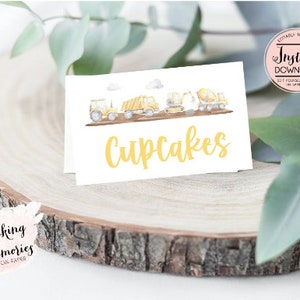 May include: A white card with a watercolor illustration of construction vehicles and the text "Cupcakes" in yellow.