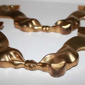 May include: Two gold-toned metal decorative door pulls shaped like a ribbon tied in a bow.