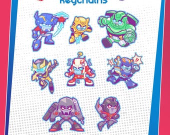Può includere: Una collezione di portachiavi dei personaggi di Transformers. I portachiavi presentano vari personaggi in stile cartone animato, tra cui Optimus Prime e Bumblebee. Le parole "Transformers" e "Keychains" sono visualizzate nella parte superiore dell'immagine.