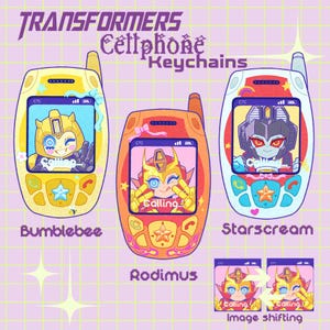 Könnte beinhalten: Drei Transformers-Handy-Schlüsselanhänger mit Bumblebee, Rodimus und Starscream. Jeder Schlüsselanhänger zeigt einen Charakter auf dem Bildschirm mit dem Text Calling. Die Designs umfassen bunte Tasten, Antennen und dekorative Schleifen auf einem Gitterhintergrund.