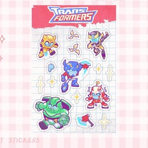 May include: A sheet of pet stickers featuring cartoon Transformers characters in various poses. The stickers include characters in yellow, blue, red, and green, with the Transformers logo at the top. The background is a grid pattern.