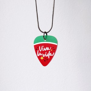 May include: A guitar pick pendant necklace with a red and green watermelon design. The pendant has the words "Viva la vida" in white script, with a yellow star accent. The necklace chain is silver.