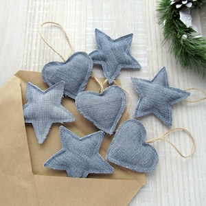 May include: A collection of seven handmade denim ornaments, including stars and hearts, with twine for hanging. The ornaments are arranged on a brown paper envelope.