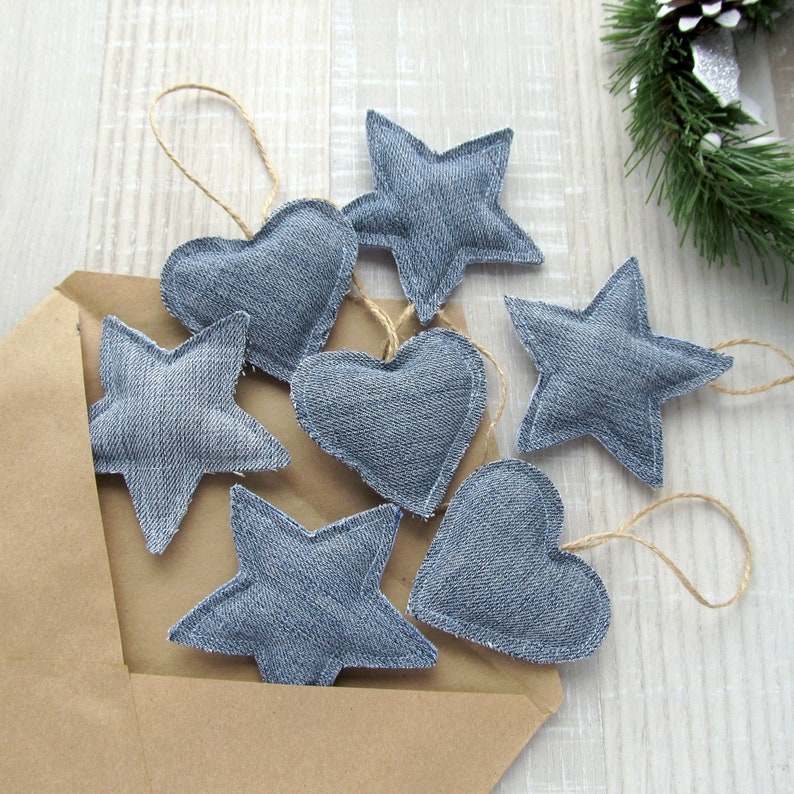 May include: A collection of seven handmade denim ornaments, including stars and hearts, with twine for hanging. The ornaments are arranged on a brown paper envelope.