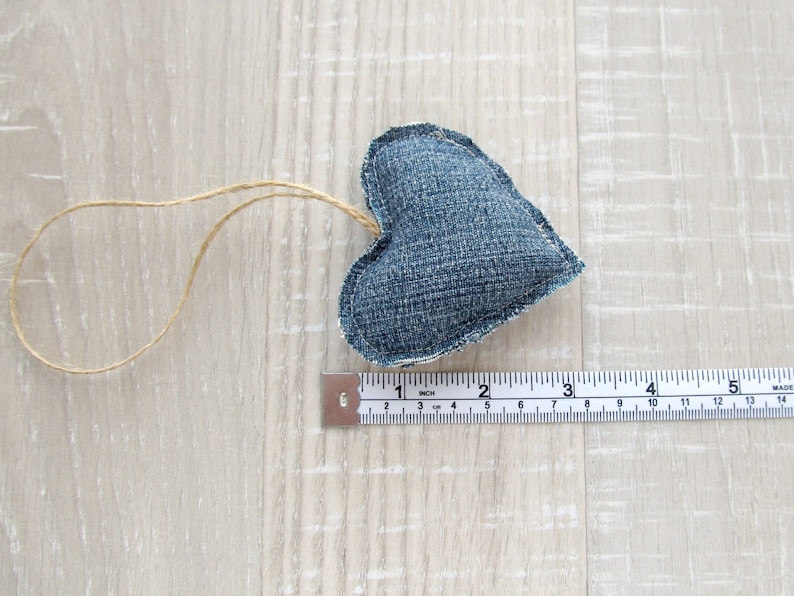 Puede incluir: Un adorno en forma de coraz&oacute;n de mezclilla azul con un lazo de cuerda para colgar. El coraz&oacute;n mide aproximadamente 5 cm de ancho.
