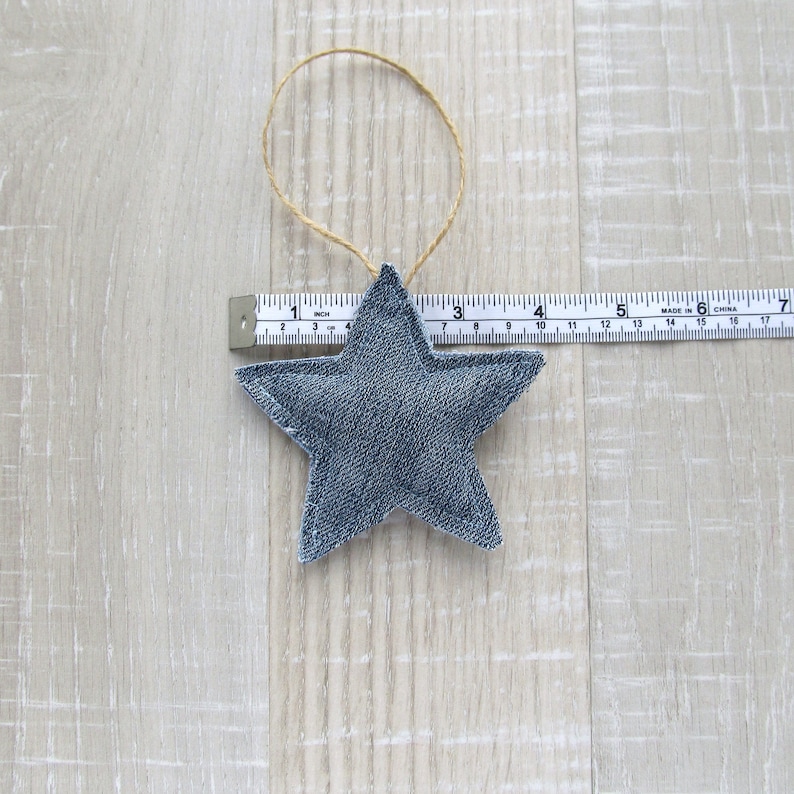 May include: A blue denim star ornament with a brown twine hanger. The star is approximately 4 inches wide.