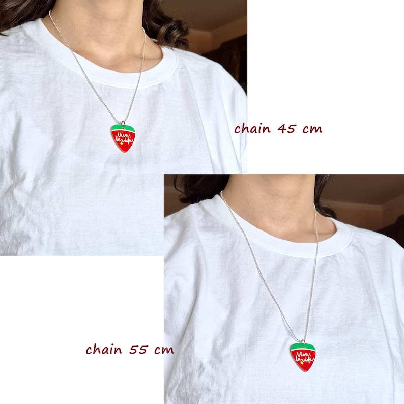 May include: A silver chain necklace with a red and green strawberry pendant. The pendant has the words "Viva la Vida" in white script. The chain is available in 45 cm and 55 cm lengths.