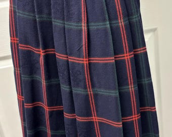 May include: A navy blue pleated skirt with a red and green plaid pattern. The skirt has a high waist and a classic design, suitable for various occasions. The fabric appears to be a medium-weight material.
