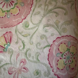 May include: White fabric with a pink, green, and yellow floral pattern. The pattern features stylized flowers and leaves.