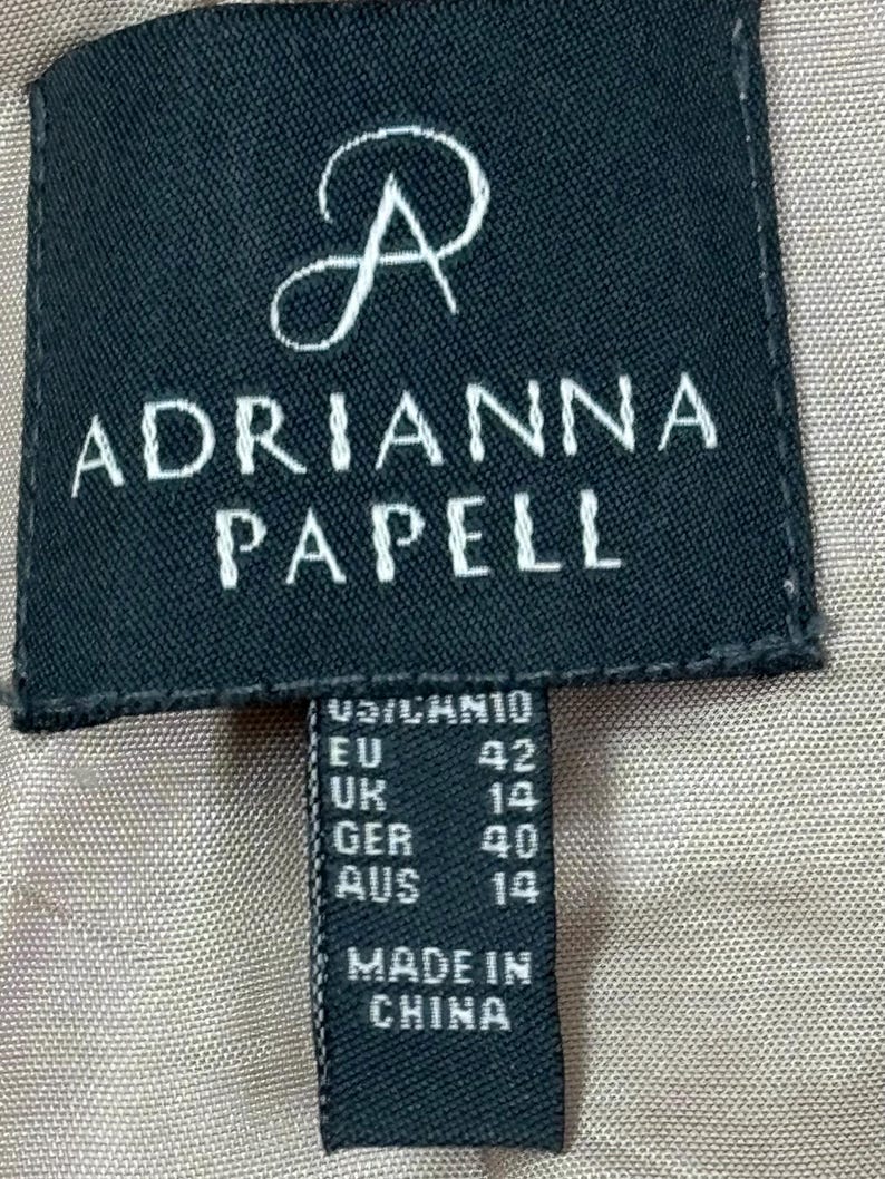 Pode incluir: Etiqueta preta e branca com o texto "Adrianna Papell" e informa&ccedil;&otilde;es de tamanho: EU 42, UK 14, GER 40, AUS 14. A etiqueta tamb&eacute;m diz "Made in China."