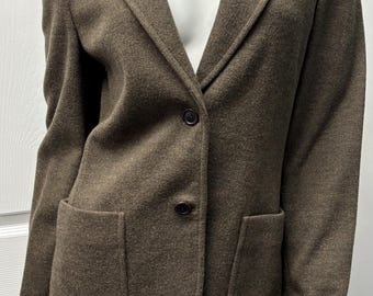 May include: A brown blazer with two front pockets and a two-button closure. The blazer has a notched lapel and is displayed on a mannequin. The fabric appears to be a textured wool blend, suitable for cooler weather.