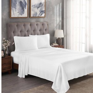 May include: A neatly made bed with crisp white sheets and pillowcases. The bed has a tufted gray headboard and is set in a bedroom with neutral-toned walls and decor. Two framed abstract art pieces hang above the bed.