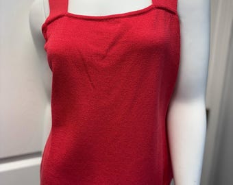 May include: A vibrant red tank top with a square neckline and wide straps. The knitted fabric has a textured appearance. The top is displayed on a white mannequin, showcasing its shape and design. This top is a stylish addition to any wardrobe.