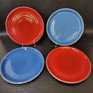 May include: Four ceramic dinner plates, two red and two blue, with a swirl design.