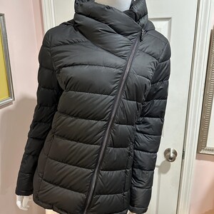 May include: A black quilted puffer jacket with a high collar and a diagonal zipper closure.