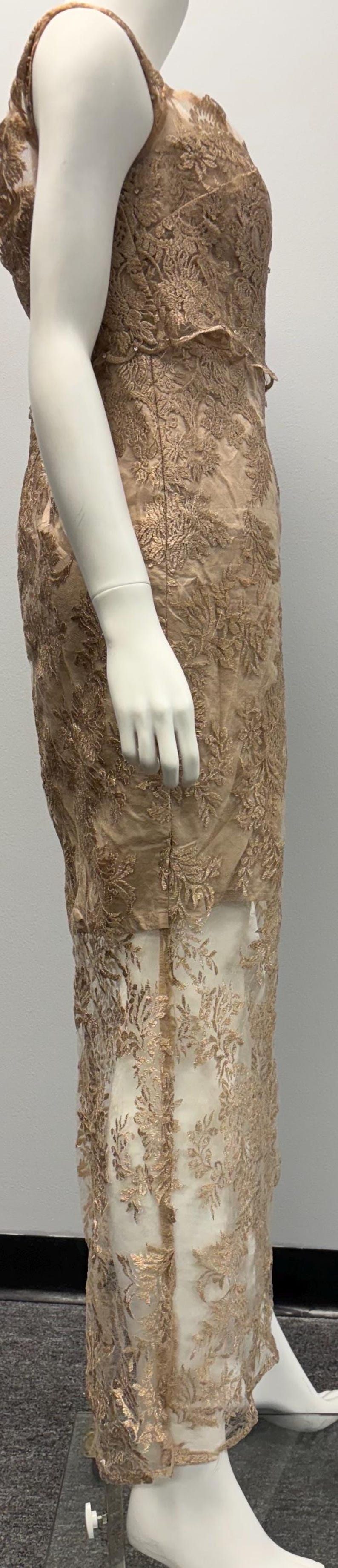 Pode incluir: Um vestido longo sem mangas com um delicado padr&atilde;o de renda floral em cor marrom claro. O vestido tem uma sobreposi&ccedil;&atilde;o transparente com um padr&atilde;o de renda semelhante.