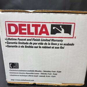May include: A white box with the Delta logo and the text "Lifetime Faucet and Finish Limited Warranty". The box also includes the text "Garant&iacute;a limitada de por vida de la llave y su acabado" and "Garantie &agrave; vie limit&eacute;e sur le robinet et son fini". The box also includes a phone number and website address.