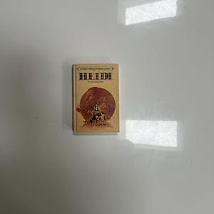 May include: A vintage hardcover book titled "Heidi" by Johanna Spyri. The cover features a sepia-toned illustration of a man, a girl, and a dog. The book is part of the "Nancy Drew Favorite Classic" series.