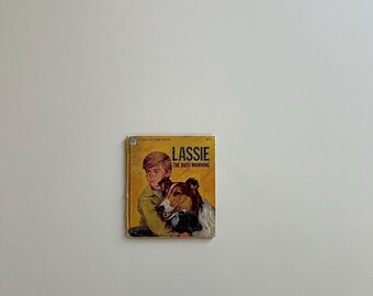 May include: A vintage children's book titled "Lassie The Busy Morning." The cover features a boy with a collie dog. The book has a yellow cover with the title in bold black letters and a picture of the boy and dog.