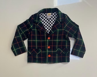 May include: A long-sleeve blazer featuring a dark green, navy blue, red, and yellow plaid pattern. The garment has three bright orange buttons down the front, two front pockets, and a black and white checkered interior lining with a Mini label.
