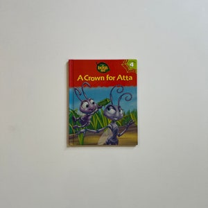 May include: A red book with a blue and green illustration of two ants on the cover. The book title is "A Crown for Atta" and the series title is "The Bugs Life".