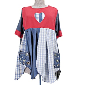 May include: A short-sleeve tunic featuring a red upper bodice with a central heart-shaped cutout revealing blue plaid fabric. The lower section is a patchwork of blue denim, light blue gingham, and plaid panels with two embroidered front pockets.