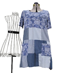 May include: A short-sleeved dress featuring a blue and white floral print on the upper section and a patchwork design on the lower section. The patchwork consists of various shades of blue denim-like fabric squares and two floral print pockets.