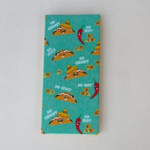 May include: A rectangular fabric item with a teal background featuring a repeating pattern of cartoon tacos wearing sombreros, red chili peppers, and tortilla chips. The text "SO CHEESY," "SO SPICY," and "SO HOT" is printed in white.