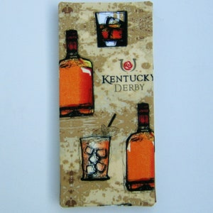 May include: A rectangular decorative item with a tan background featuring illustrations of whiskey bottles and glasses with ice. The text "Kentucky Derby" is also visible. The item has a vintage, hand-drawn style.