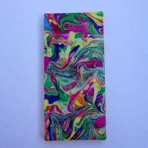 May include: A rectangular item with a vibrant, swirled pattern in shades of green, pink, yellow, blue, and orange. The design resembles a marbled effect, creating a dynamic and colorful visual. The item is set against a plain white background.