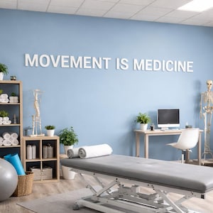 May include: A physiotherapy room featuring a grey treatment table, exercise ball, and shelving. The wall displays the text "MOVEMENT IS MEDICINE". A skeleton and anatomical chart are also present.