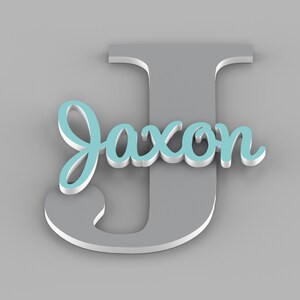 May include: A gray wooden letter J with the name Jaxon written in light blue cursive letters on top of it.