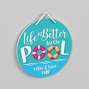 May include: A round turquoise sign with white text that reads "Life is Better by the Pool" with two colourful life preservers. The text "relax & have fun" is at the bottom of the sign.