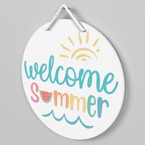 May include: White round sign with the text "Welcome Summer" in colorful script. The sign features a sun with rays and a slice of watermelon.