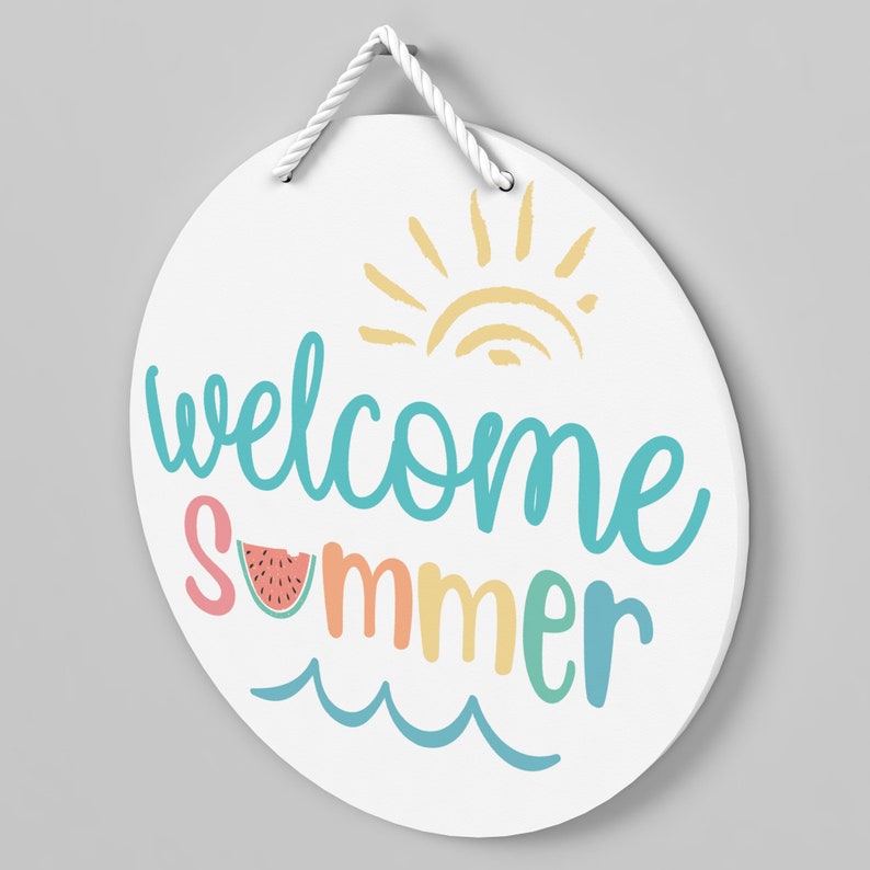 May include: White round sign with the text "Welcome Summer" in colorful script. The sign features a sun with rays and a slice of watermelon.