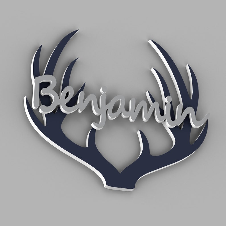 May include: A decorative wall art piece featuring the name "Benjamin" in a silver script font, set against a navy blue antler design with white trim. The artwork has a 3D effect, creating depth and visual interest.