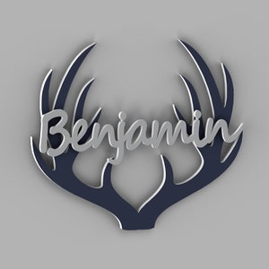 May include: A decorative wall hanging featuring the name "Benjamin" in silver script, set against a navy blue antler design with white accents. The design is set against a light gray background.