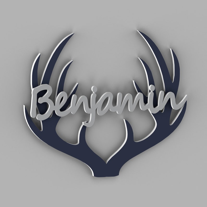 May include: A decorative wall hanging featuring the name "Benjamin" in silver script, set against a navy blue antler design with white accents. The design is set against a light gray background.