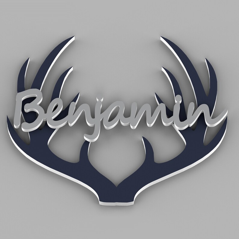 May include: A decorative wall hanging featuring the name "Benjamin" in silver script, set against a navy blue antler design with a white outline. The piece is designed to be mounted on a wall.