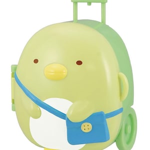 以下が含まれることがあります： 青いストラップと小さな青いバッグが付いた、緑と黄色のペンギン型のスーツケース。スーツケースにはハンドルと車輪が付いています。