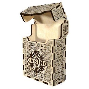 May include: A wooden casino-themed box with an open lid. The box is light-colored with dark etched details, including the word "CASINO" and other casino-related text. The lid is also etched with a decorative pattern.