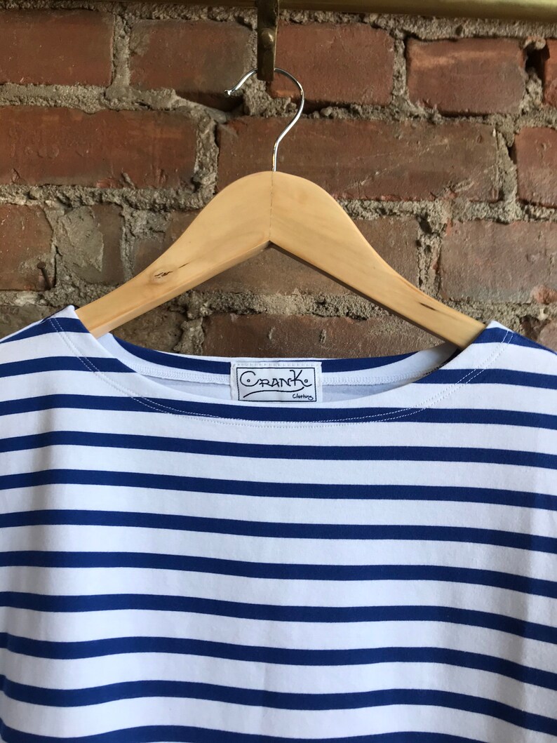 May include: A white and blue striped t-shirt with a navy blue collar and a "Crank Clothing" label.