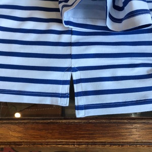 May include: A white and blue striped shirt with a side seam detail. The shirt is made of a soft, comfortable fabric.